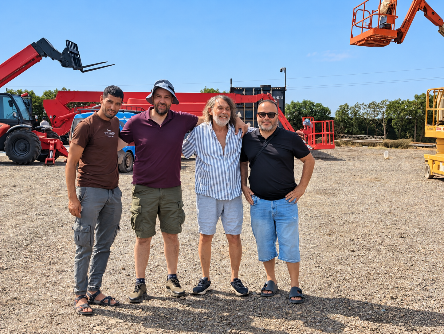 Pierre et Abdelmajid Cabana avec leurs clients sur un terrain industriel, devant des engins de chantier, après une prospection d’eau souterraine. Marrakech